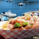 View of a traditional Maine Lobster Roll served with chips.